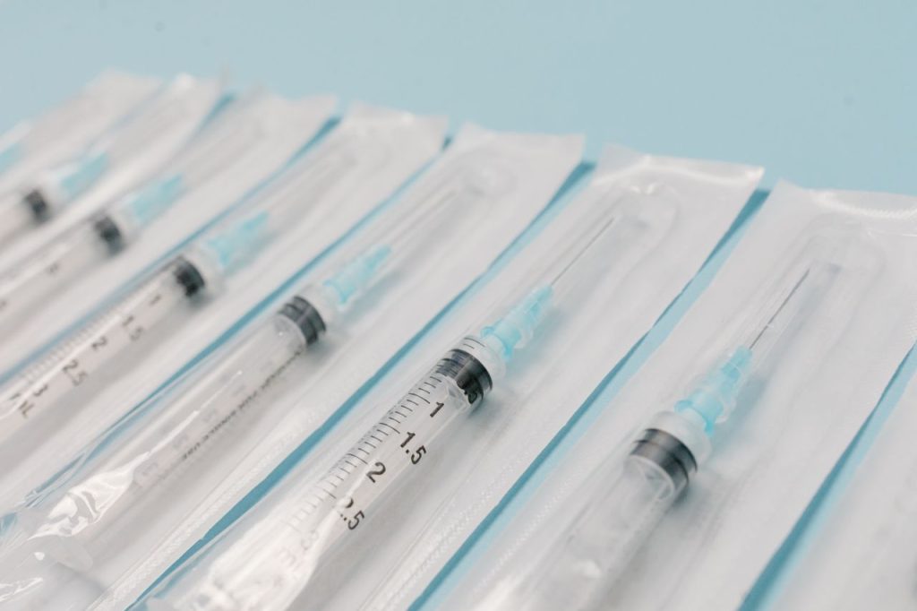 pexels-photo-7722555-7722555-1 Close-up of sterile syringes aligned on a light blue surface, highlighting medical equipment.